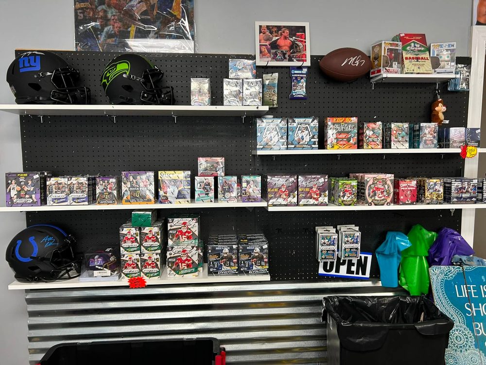Shelves of sealed hobby boxes, mega boxes and blasters with signed helmets above