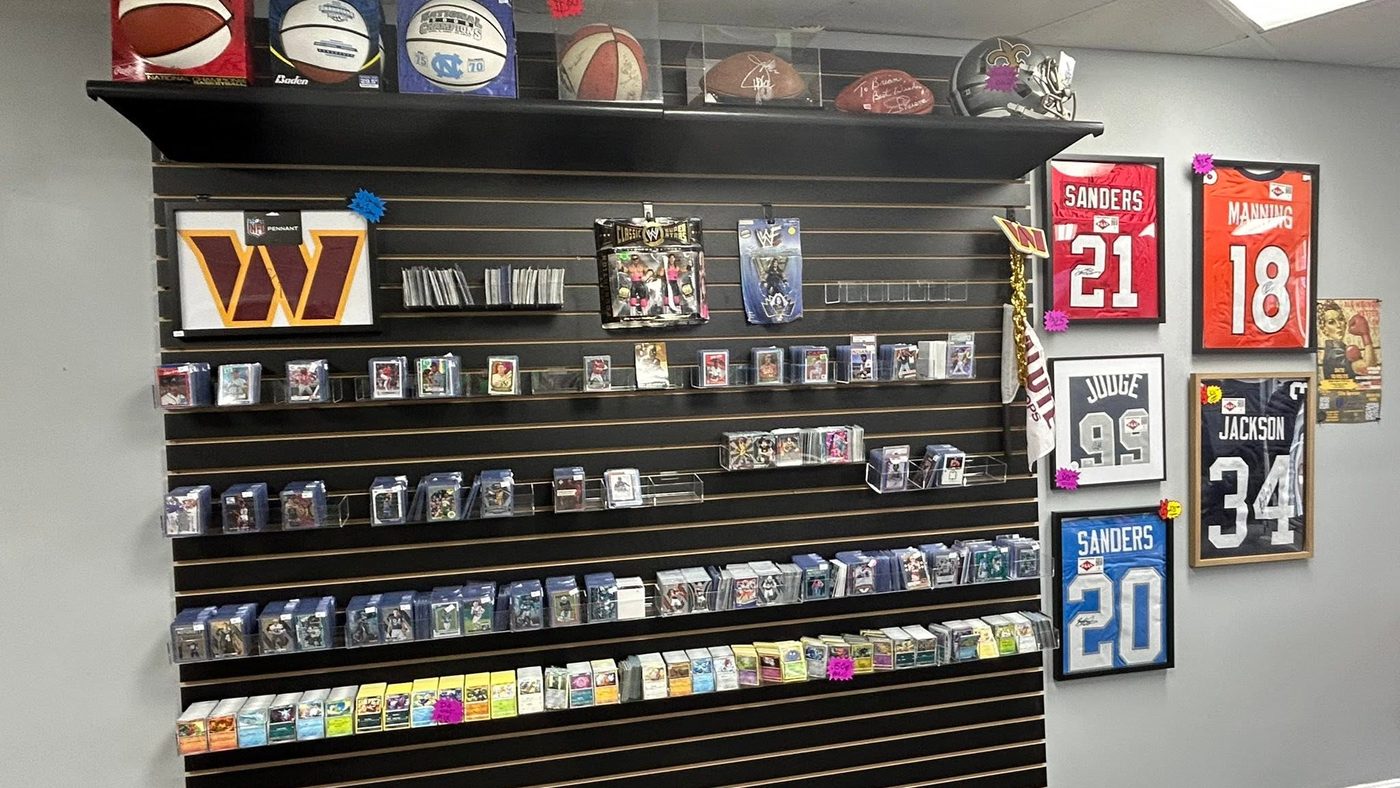 Slat wall lined with raw singles in sleeves, framed jerseys and signed footballs